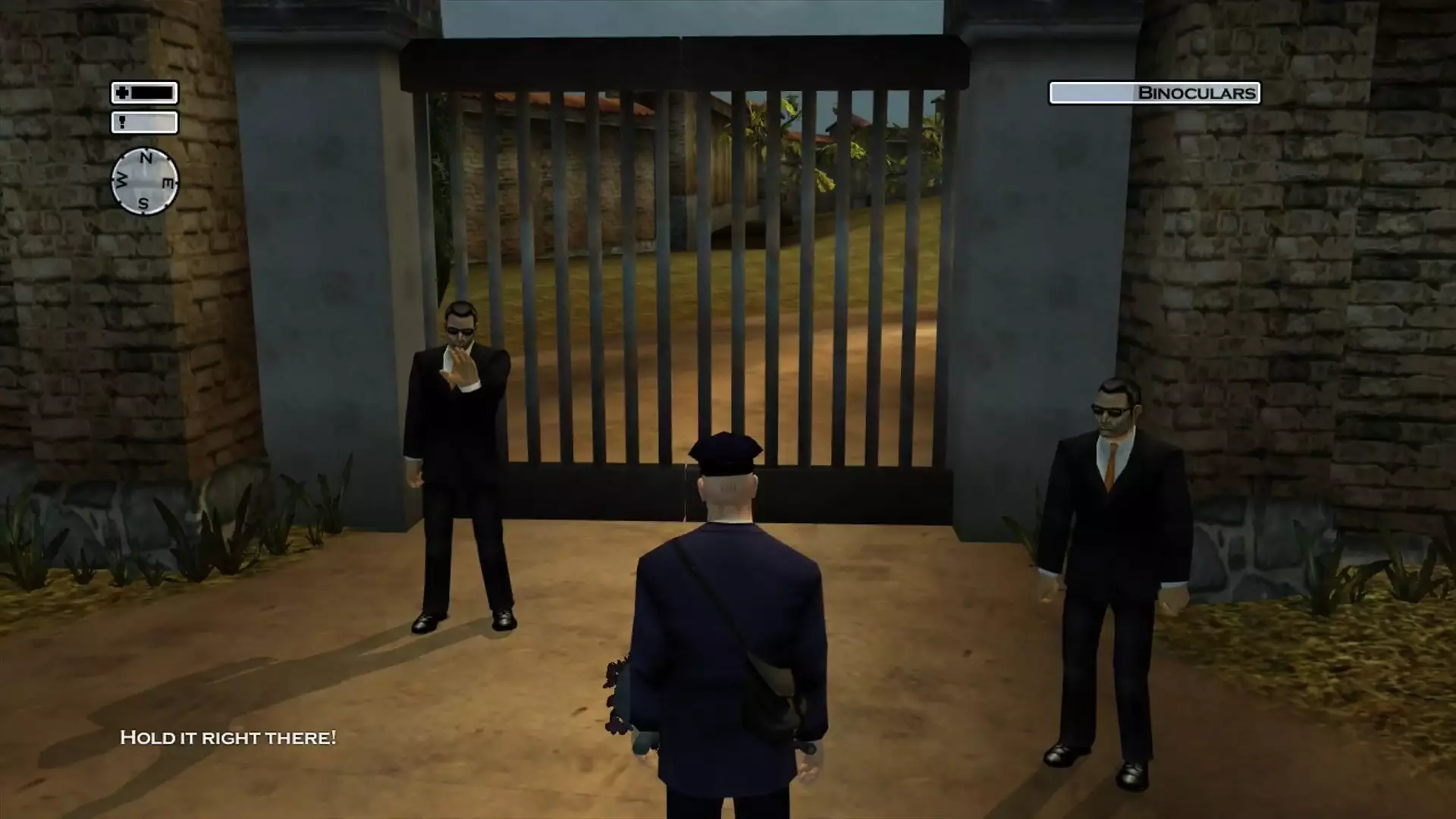 47 versucht sich als Postbote verkleidet in eine Villa zu schleichen und wird dabei am Eingang angehalten.